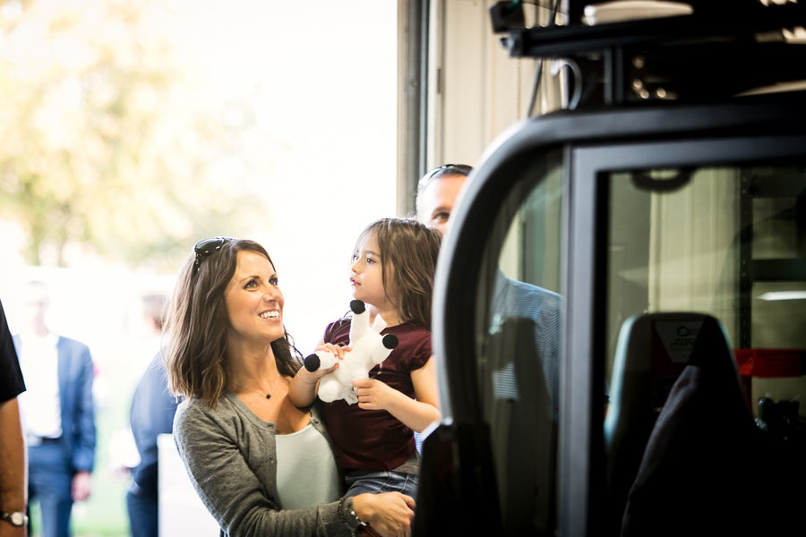 Woman holding a child next to a vehicle